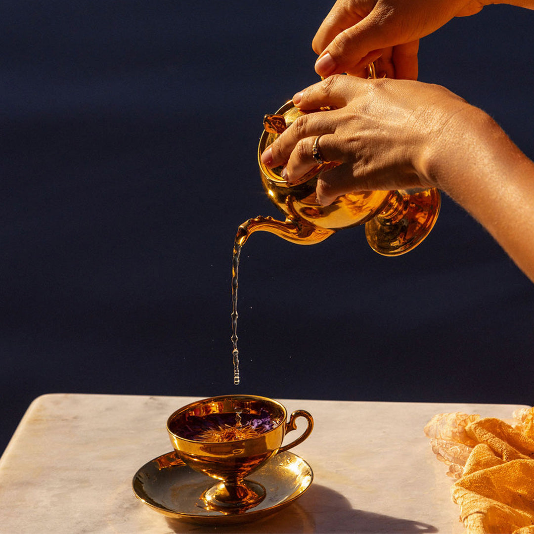 a cup of blue lotus tea, gold teapot and cup